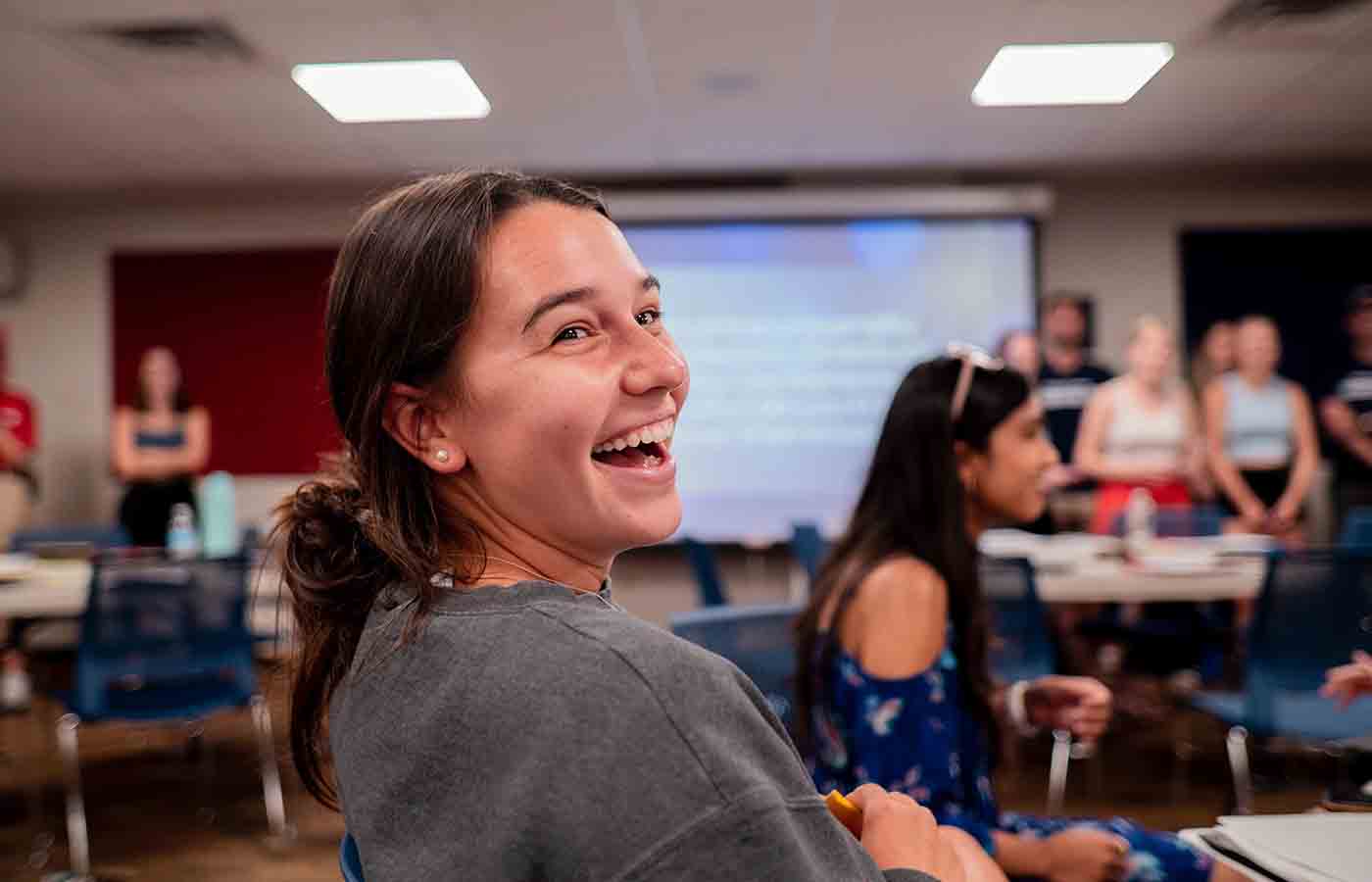 A DeSales student laughing at an indoor meeting