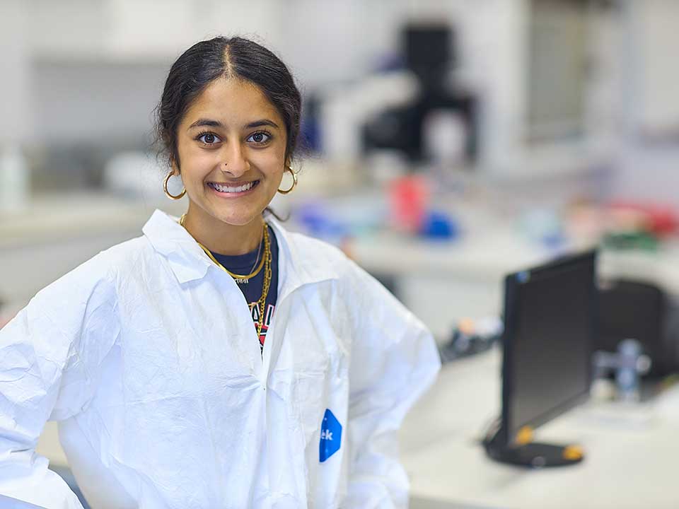 female student wearing a lab coat in a lab