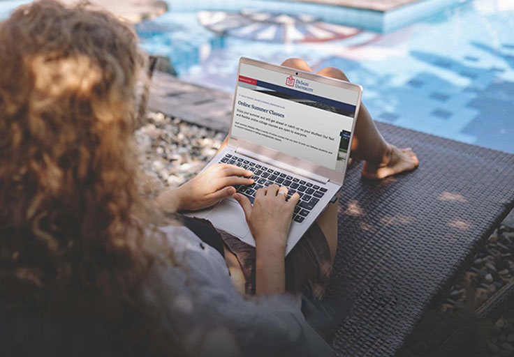 young woman taking online courses at DeSales while lounging poolside
