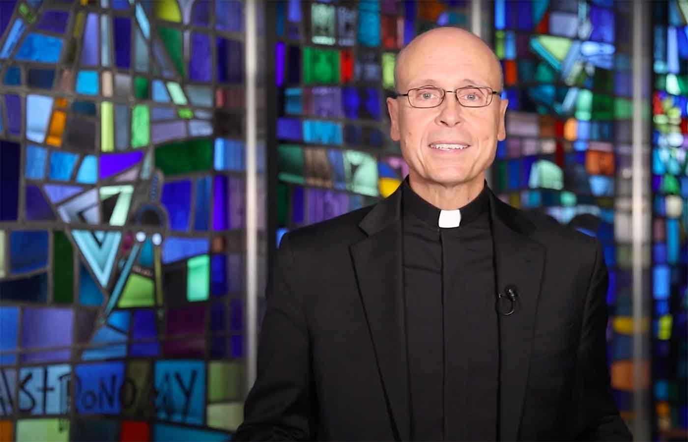 father jim speaking in front of stained glass windows