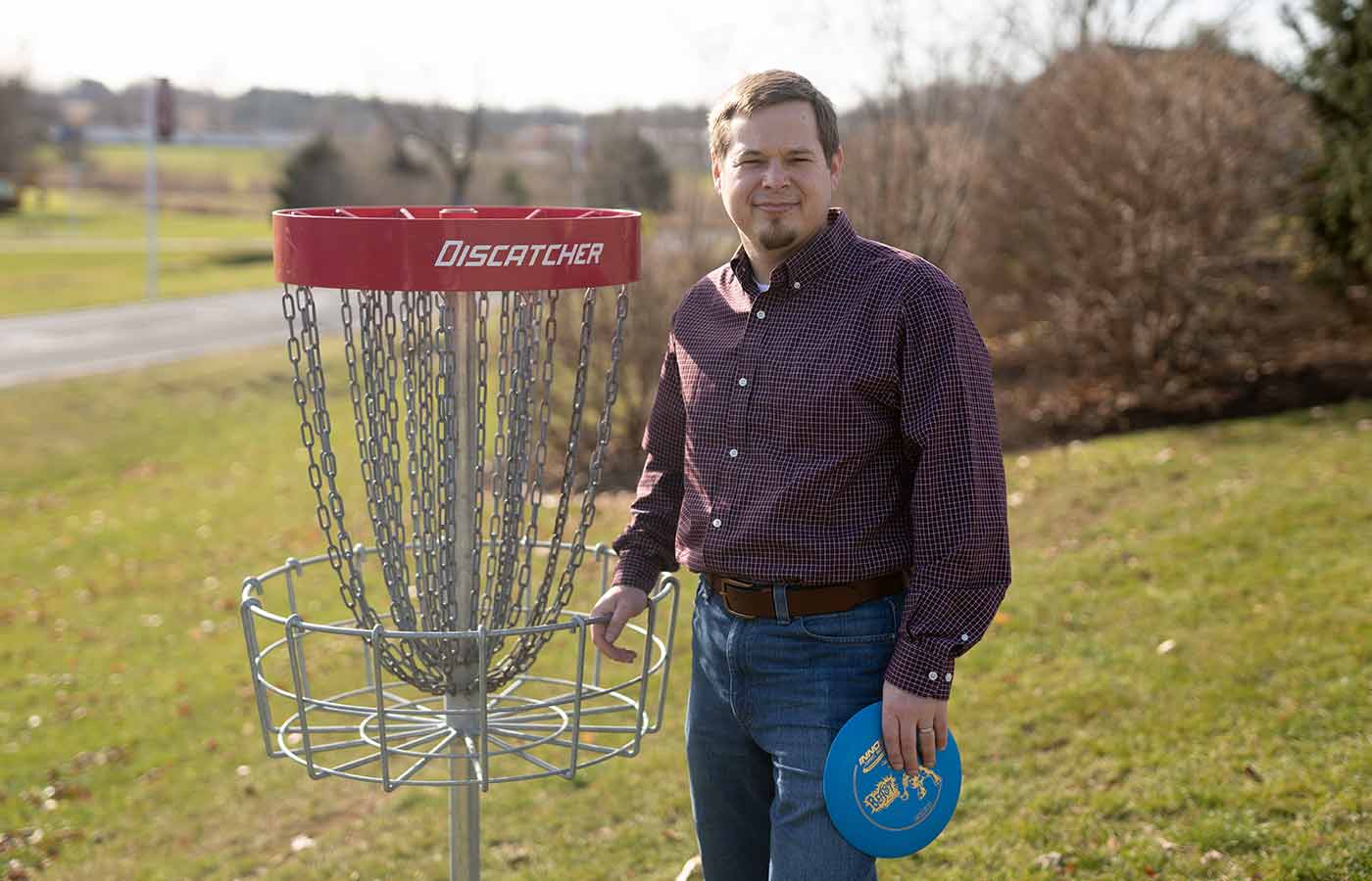 Joe Leese standing by a disc golf course