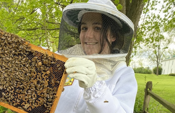 Lucy Winn holding a honeycomb frame with bees