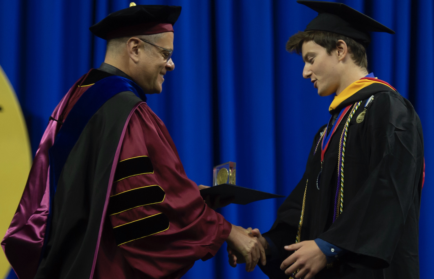 Nolan Beck and Father Kevin Nadolski Shaking Hands at Commencement