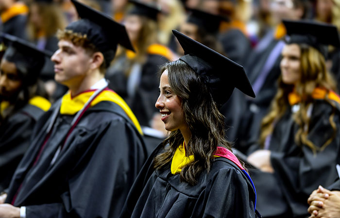 students wearing caps and gowns sitting at commencement ceremony