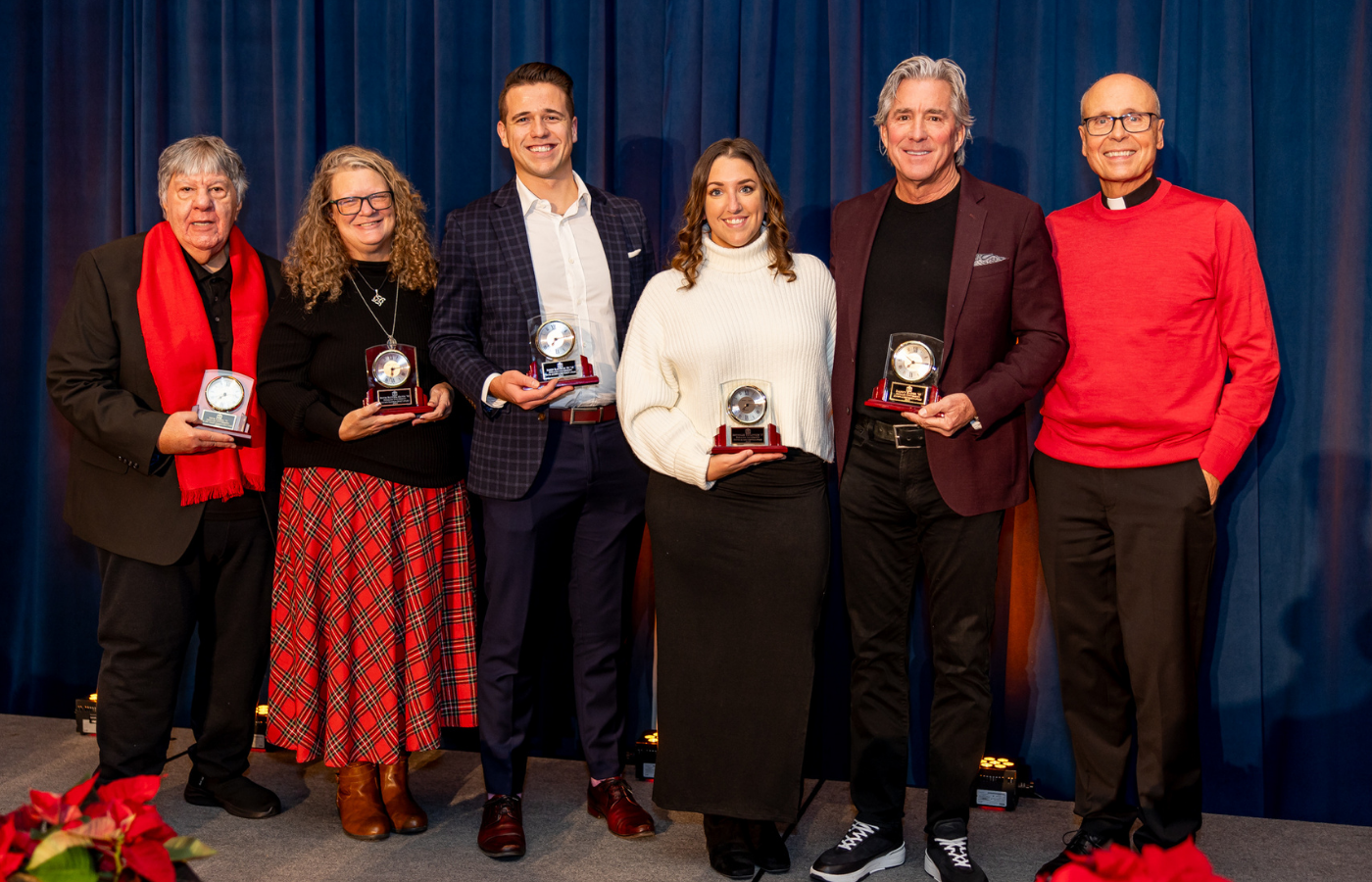 DeSales University Alumni Award honorees pose together on stage holding their awards.