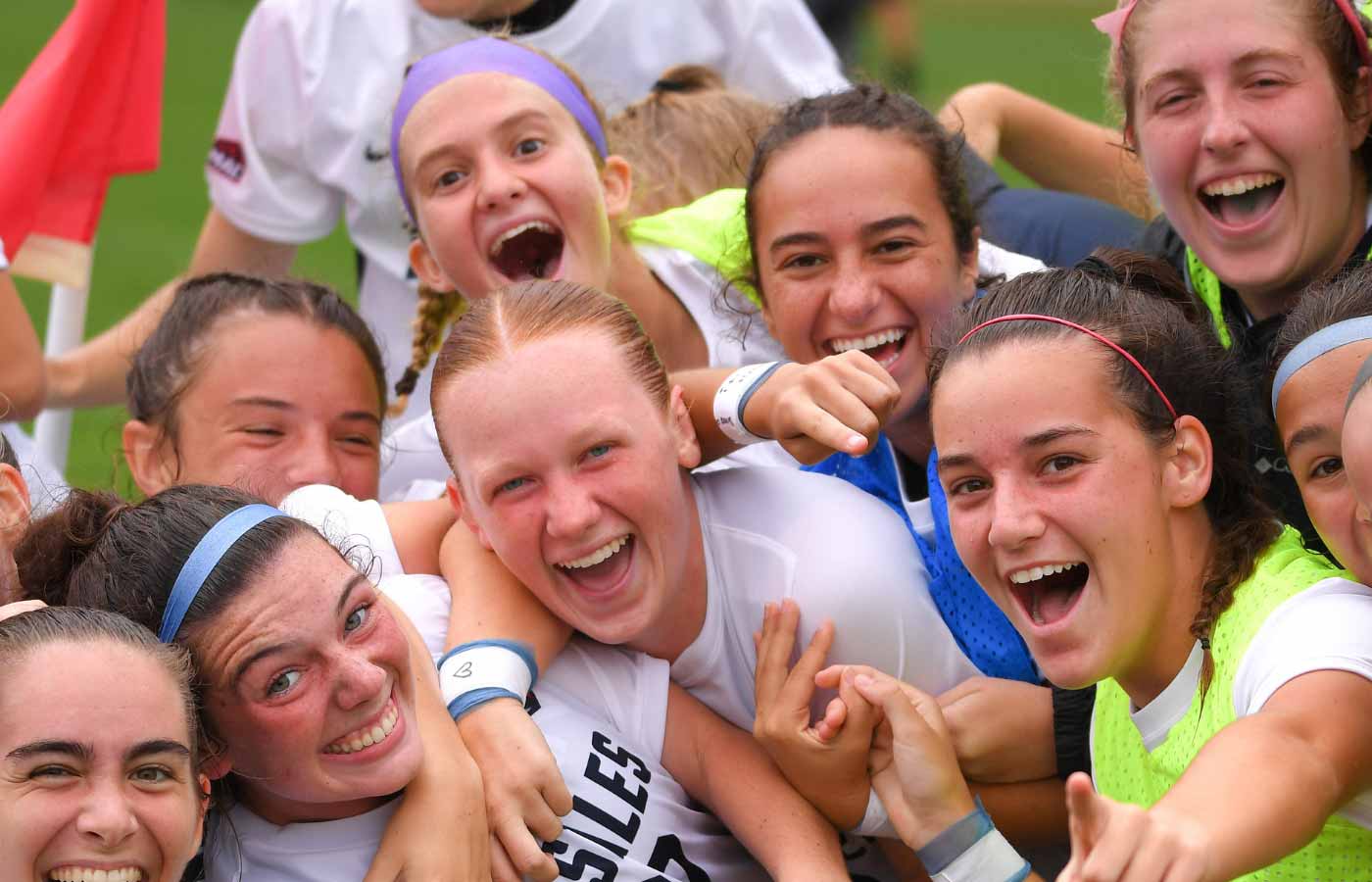 DeSales women’s soccer players crowd together on the field, laughing and cheering as they celebrate.